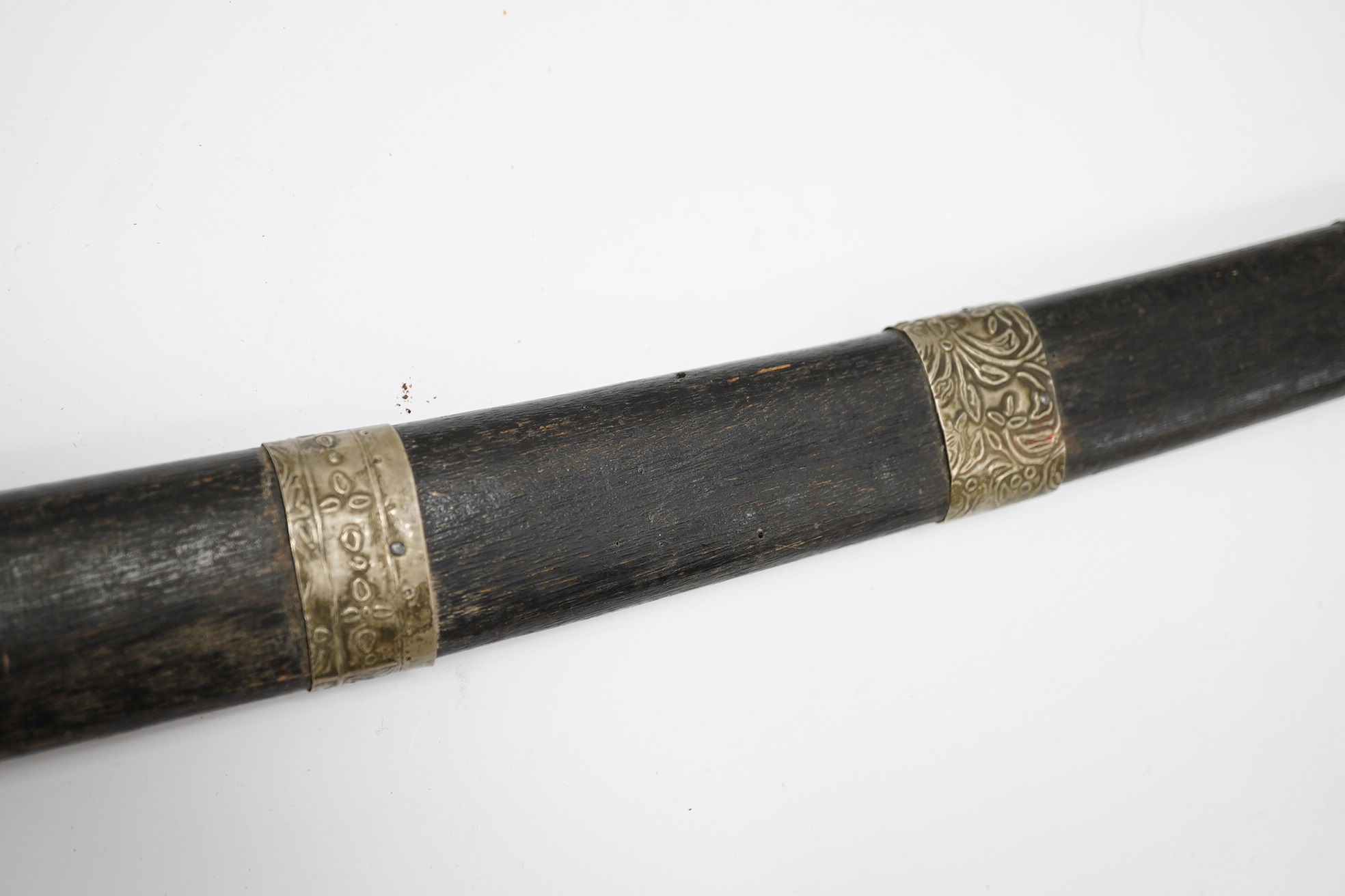 A Malaysian sword Parang, with broad curved pattern welded single edged blade, carved horn pommel, and embossed nickel mounts, in its wooden scabbard. Condition - good